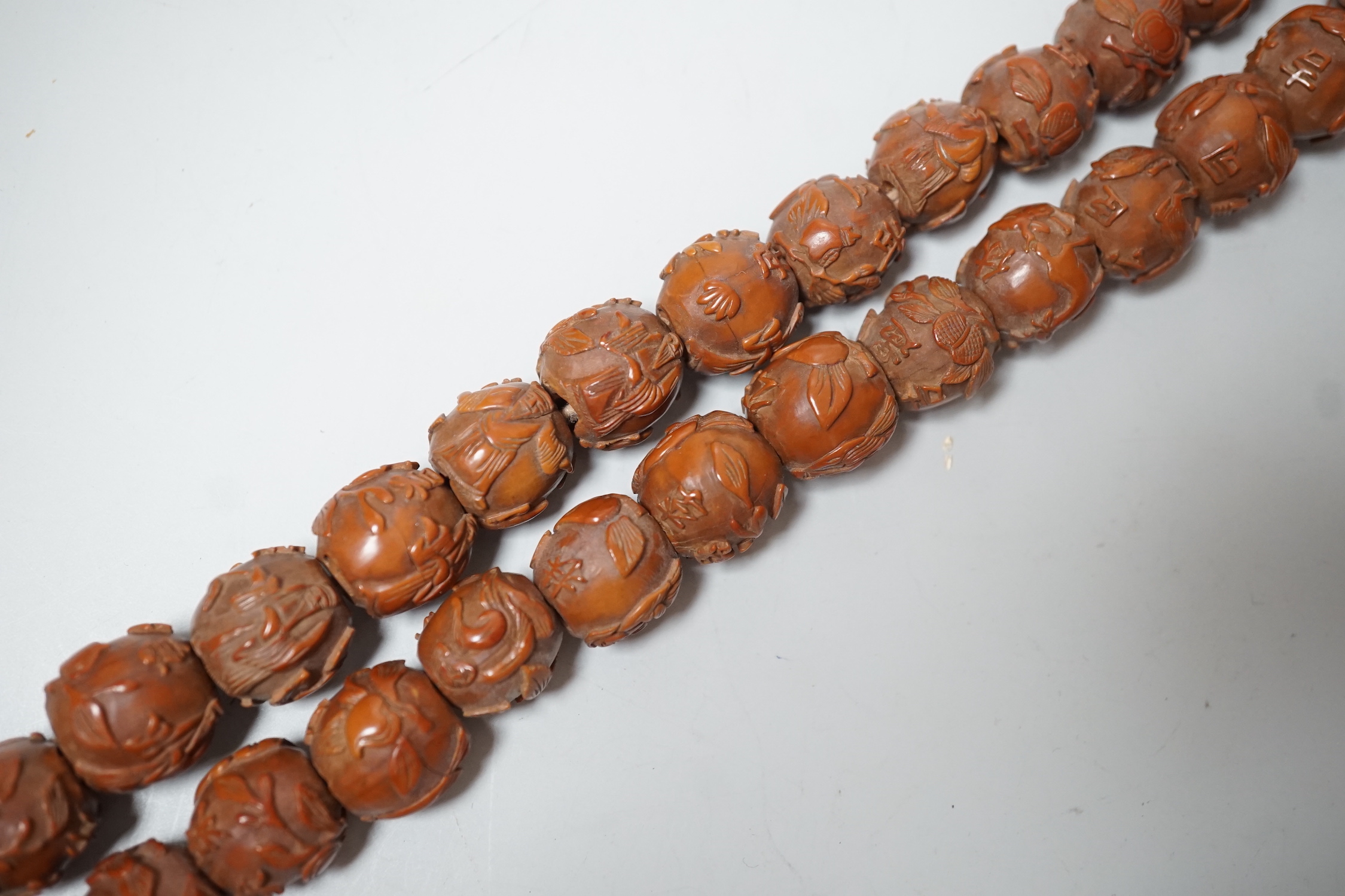 A Chinese necklace of 94 carved coquilla nuts/peach stones